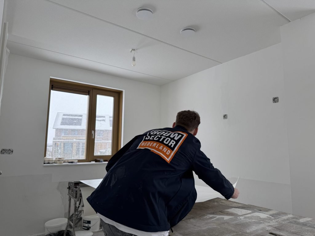 Behanger van Bouwsector Nederland snijdt een baan renovlies op maat aan de plaktafel
